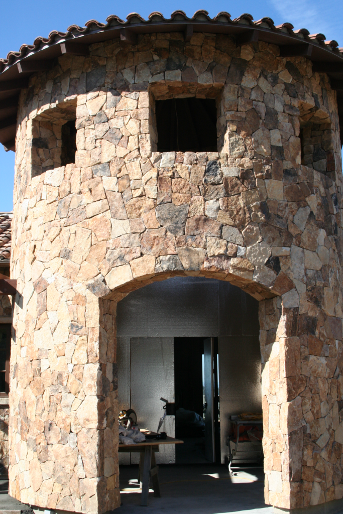 exterior of a building features seamless cut stone veneer; the windows and doorway remain unfinished
