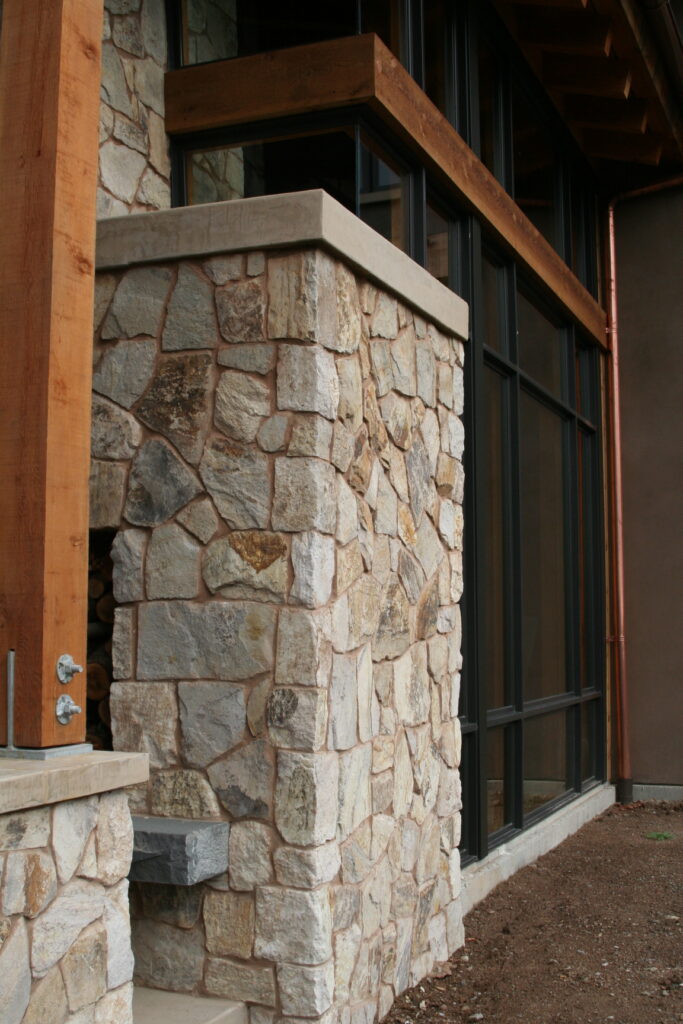 closeup of the cut stone veneer surrounding the walls of a winery's outdoor patio; the roof is supported by beautiful red wood beams and exposed hardware