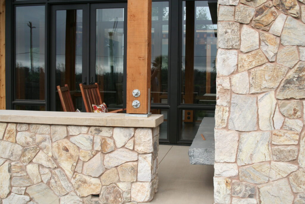 closeup of the cut stone veneer surrounding the walls of a winery's outdoor patio; the roof is supported by beautiful red wood beams and exposed hardware