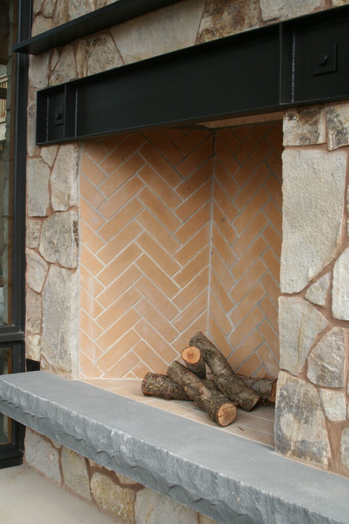 closeup of the interior of an outdoor fireplace; the interior of the fireplace features bricks laid in a herringbone pattern