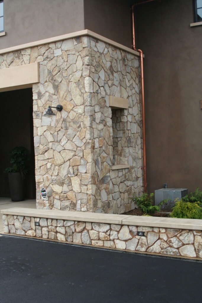 closeup of cut stone facade of a winery; a copper utility pipe rises from the ground to the rooftop