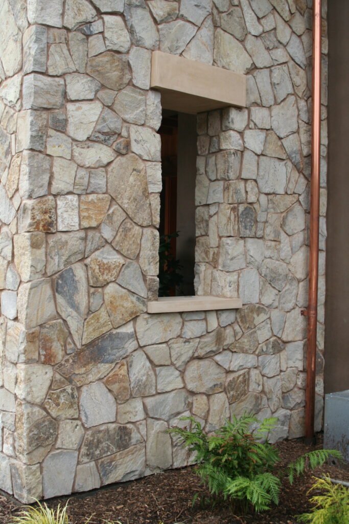 closeup of cut stone facade of a winery; a copper utility pipe rises from the ground to the rooftop