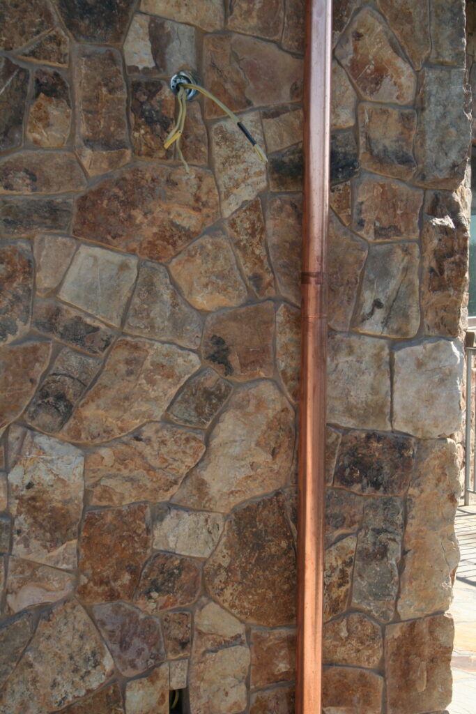 closeup of cut stone veneer and copper utility pipe
