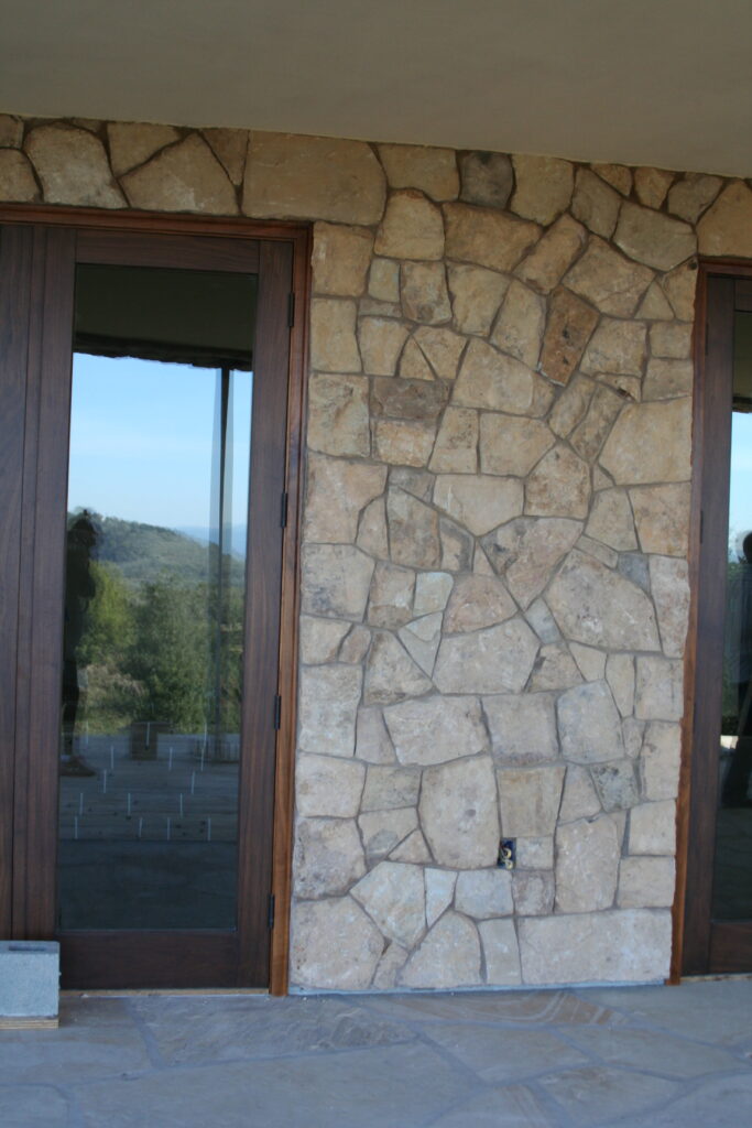 exterior of a building features seamless cut stone veneer that matches the garden planters just outside the building; the doors leading to the exterior feature bronze metal accents