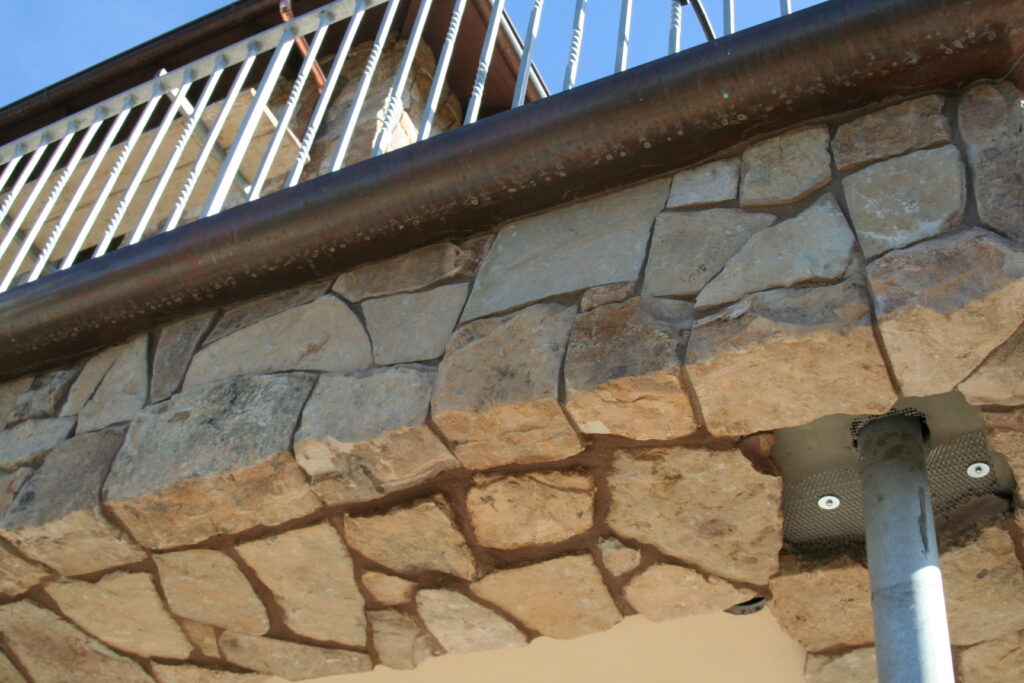 closeup of the stone veneer and iron gutters of the second story balcony