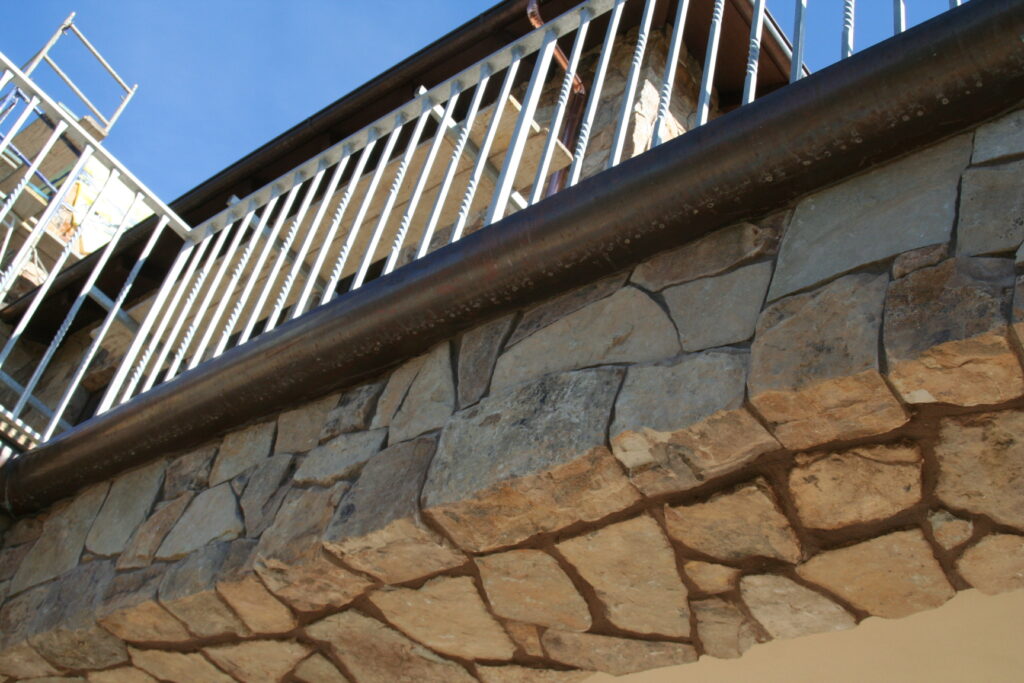 closeup of the stone veneer and iron gutters of the second story balcony