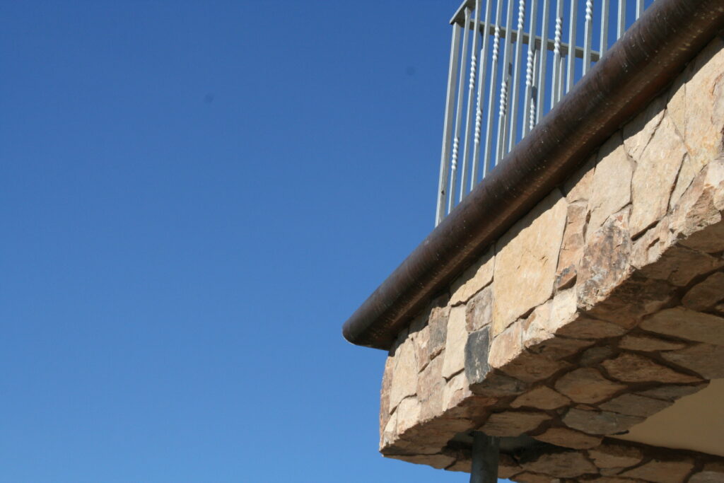 closeup of the stone veneer and iron gutters of the second story balcony