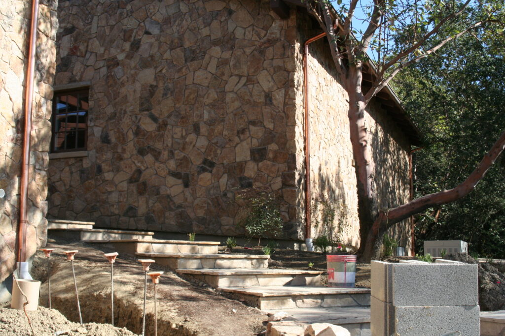 the team at Masonry by Conrad works on the cut stone veneer for a Santa Rosa estate high up in the hills; cut stone steps lead towards the camera and away from the residence