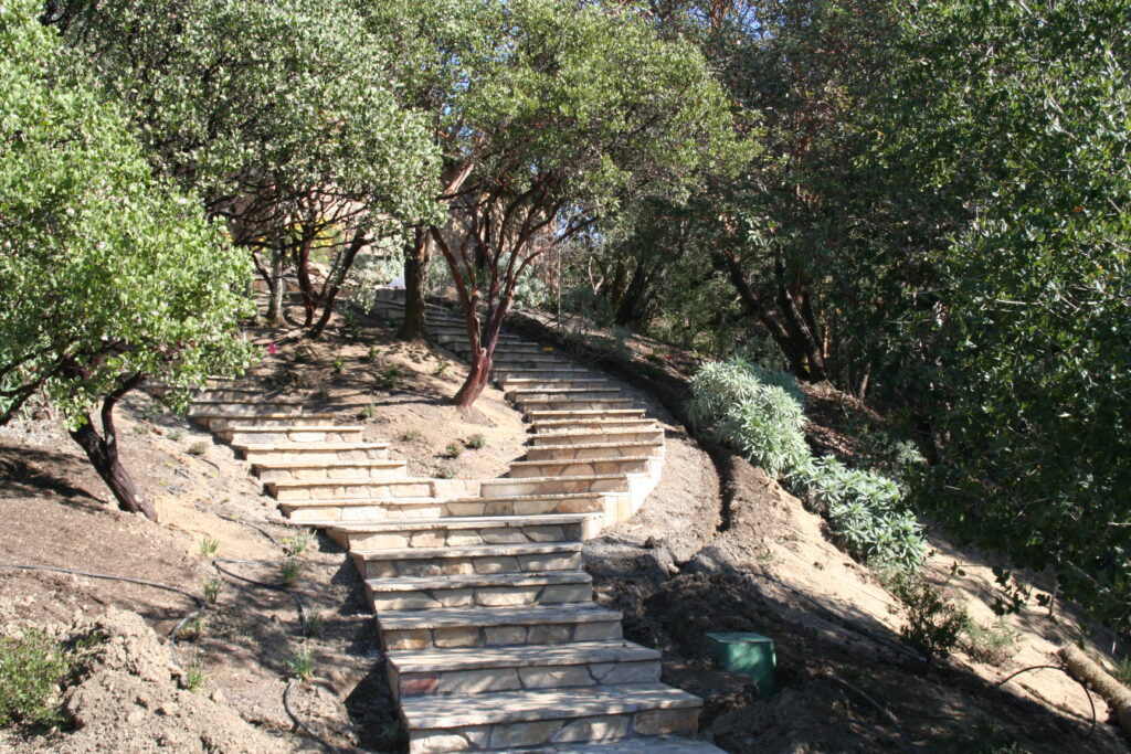 cut stone stairway with stone treads leads up a hill through a garden to a residence