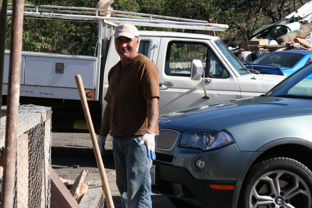 Conrad poses for the camera in front of parked cars outside the construction site