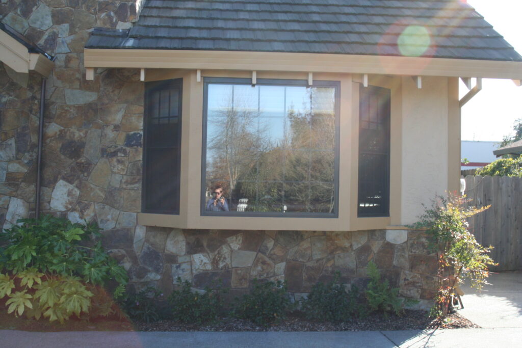 cut stone veneer chimney viewed from the outside of a Santa Rosa residence; the cut stone continues along the skirting of the house