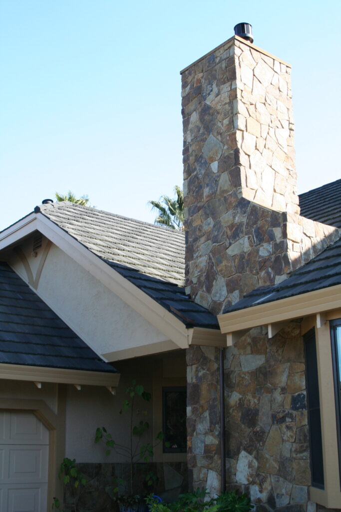 cut stone veneer chimney viewed from the outdoor; the cut stone continues along the skirting of the house