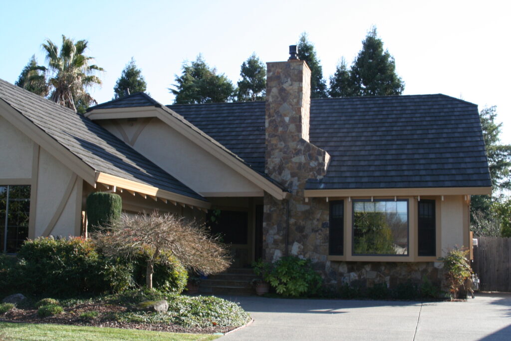 cut stone veneer chimney viewed from the outside of a Santa Rosa residence; the cut stone continues along the skirting of the house