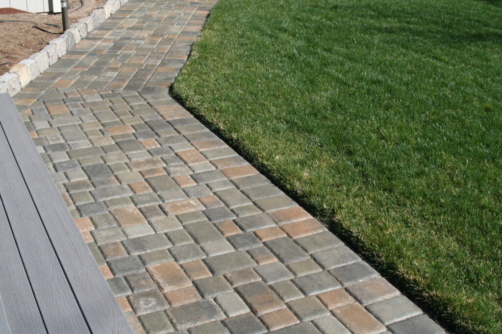 patio pavers create a walkway surrounding a manicured lawn