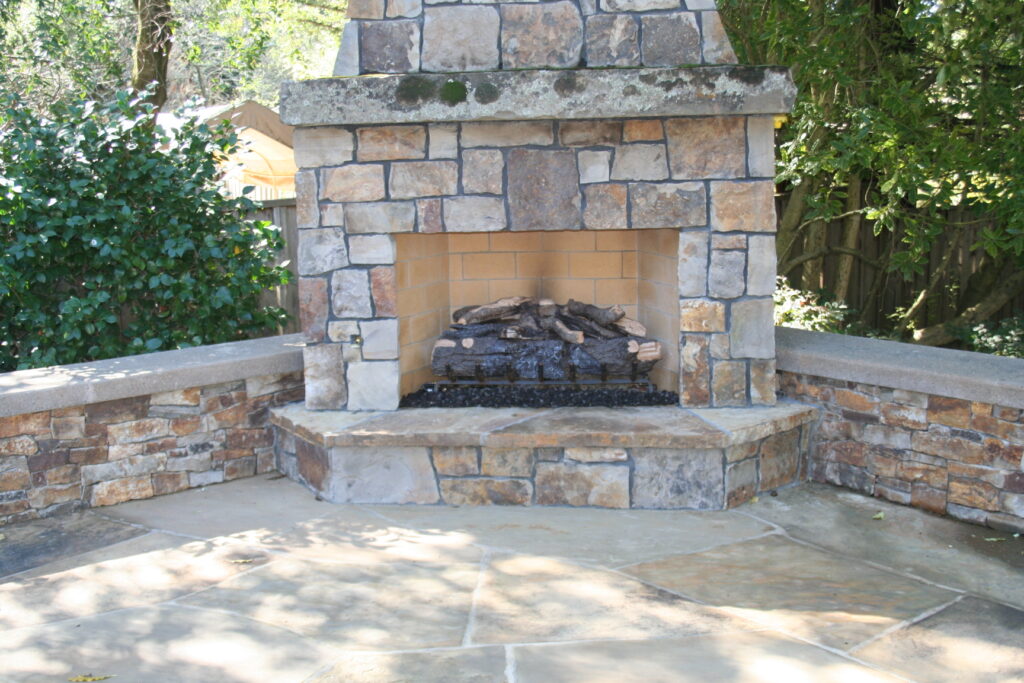 cut stone veneer for an outdoor fireplace with faux wood burner