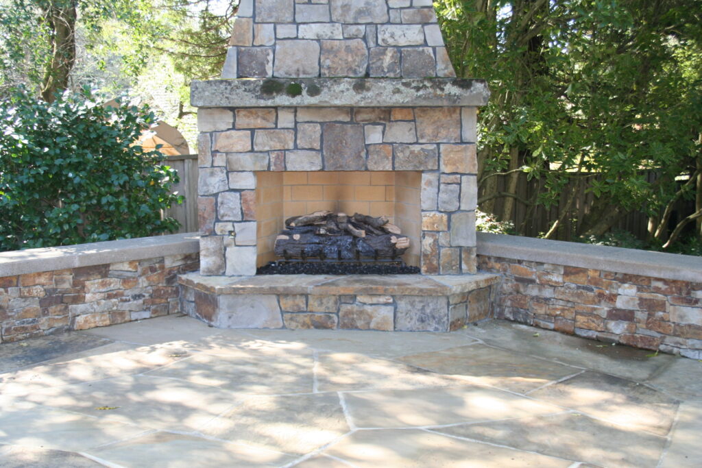 cut stone veneer for an outdoor fireplace with faux wood burner