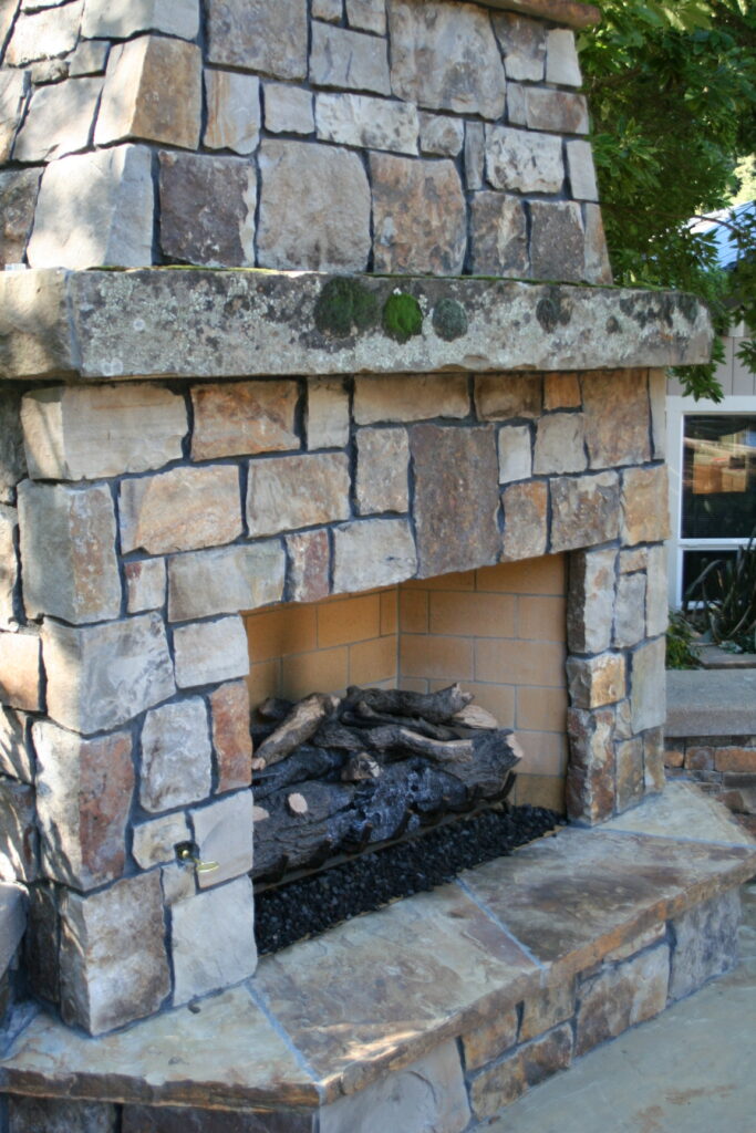 cut stone veneer for an outdoor fireplace with faux wood burner