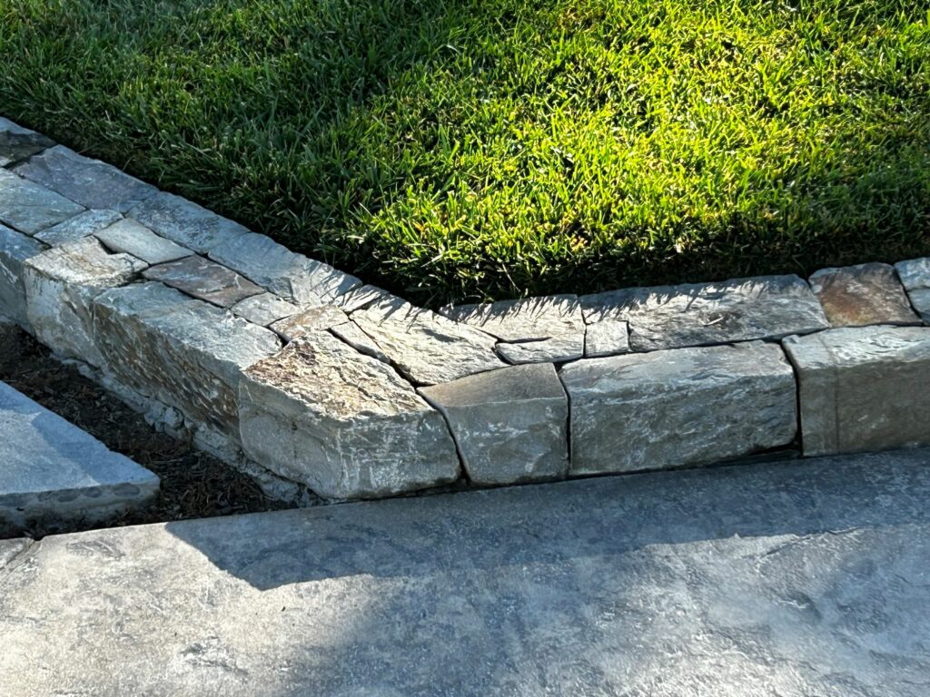cut stone landscape divider surrounding a perfectly manicured lawn